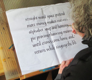 Calligraphy artist and workshop teacher Pam Galvani touching up her italic calligraphy in pen and ink
