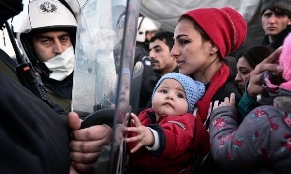Mother and child are marooned in a refugee camp in Idomeni Greece, facing local police. (Photo: The Guardian)